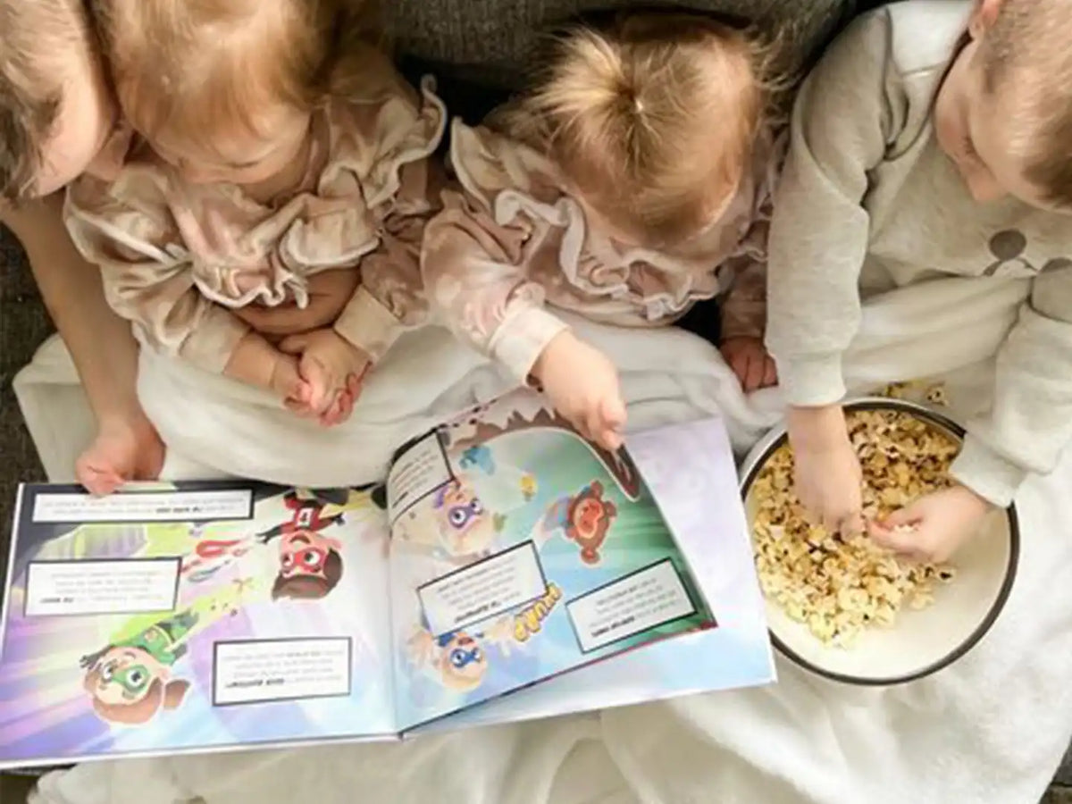 Des enfants dévorant des pop corns et leur livre personnalisé pour 4 petits.