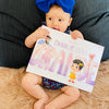 Une petite fille dévorant son livre personnalisé pour Papa, une idée de cadeau originale et unique pour la fête des pères ou Noël.