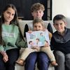 Quatre adorables frères et sœurs sourient et lisent leur propre livre personnalisé créé juste pour eux, ce qui constitue un excellent cadeau personnalisé pour quatre enfants.