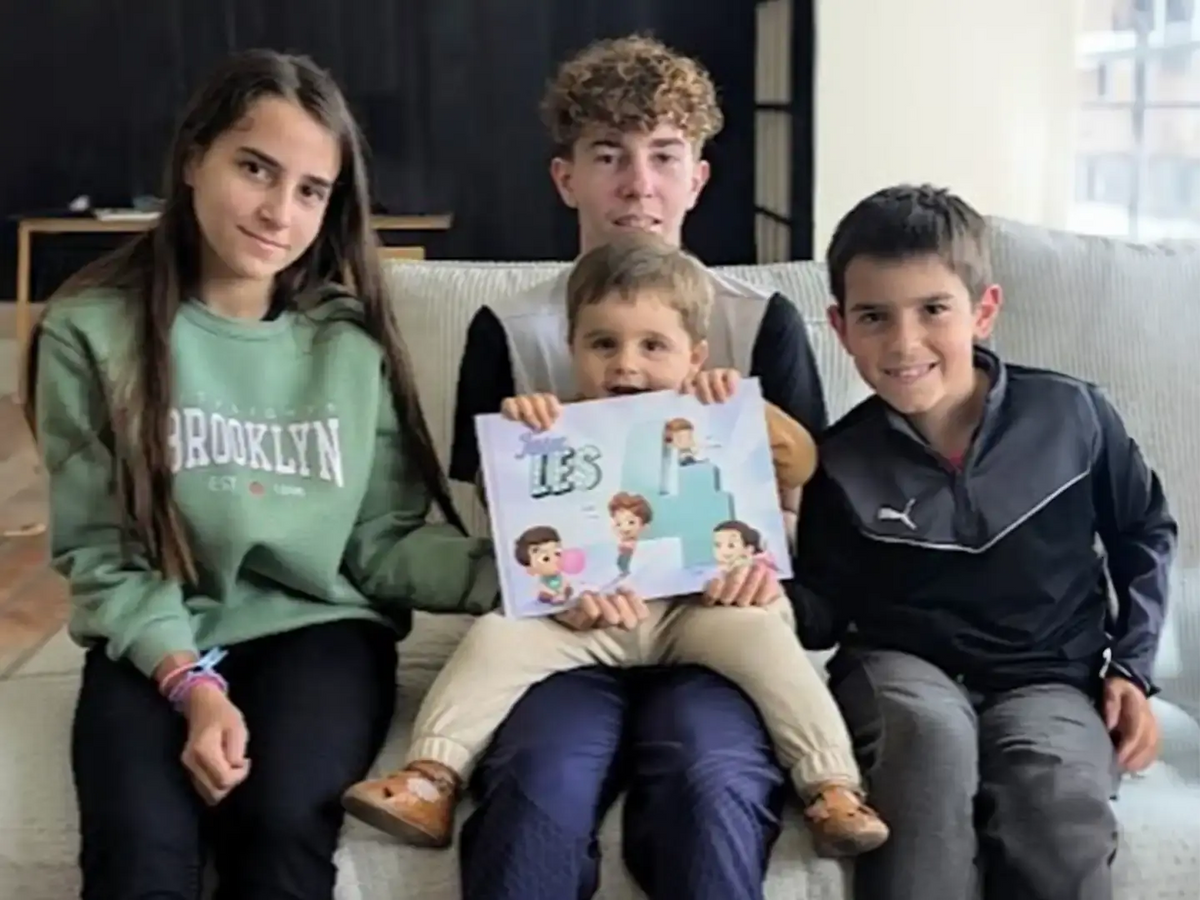 Quatre adorables frères et sœurs sourient et lisent leur propre livre personnalisé créé juste pour eux, ce qui constitue un excellent cadeau personnalisé pour quatre enfants.